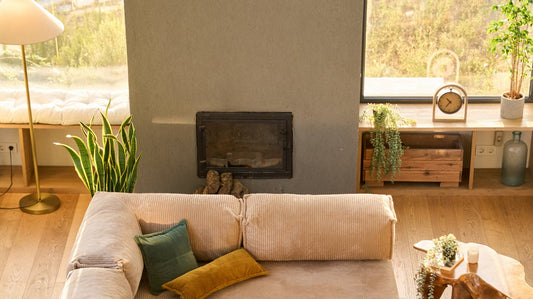 Beige modular sofa in a designed living room with a fireplace, tall window and plants