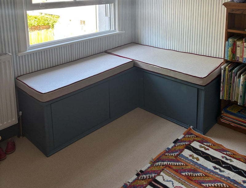 Customer photo: L-shaped corner window seat with cream cushions and red piping