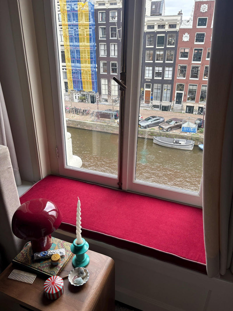Customer photo: red cushion fitted into a deep window frame above a canal