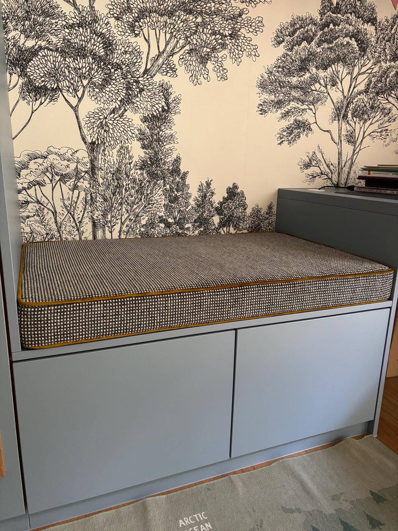 Customer photo: textured cushion with gold piping on a reading-nook cabinet